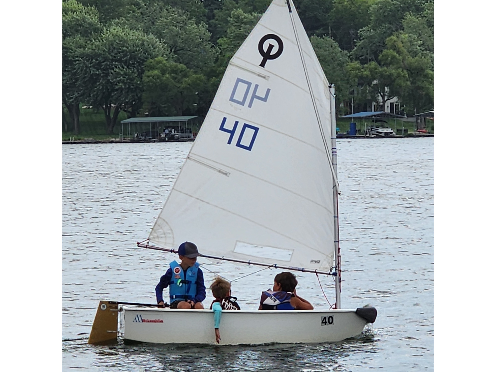 Three young sailors in an Optimist dinghy